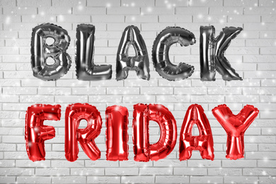 Phrase BLACK FRIDAY made of foil balloon letters against white brick wall