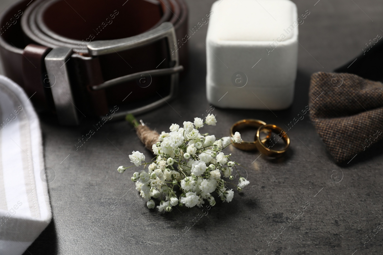 Photo of Wedding stuff. Composition with stylish boutonniere on black table, closeup