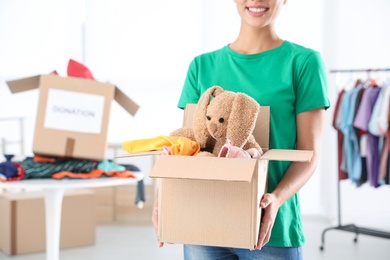 Young woman holding box with donations indoors