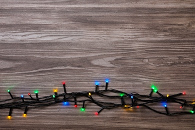 Christmas lights on wooden table, top view. Space for text