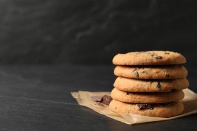 Photo of Delicious chocolate chip cookies on black table. Space for text