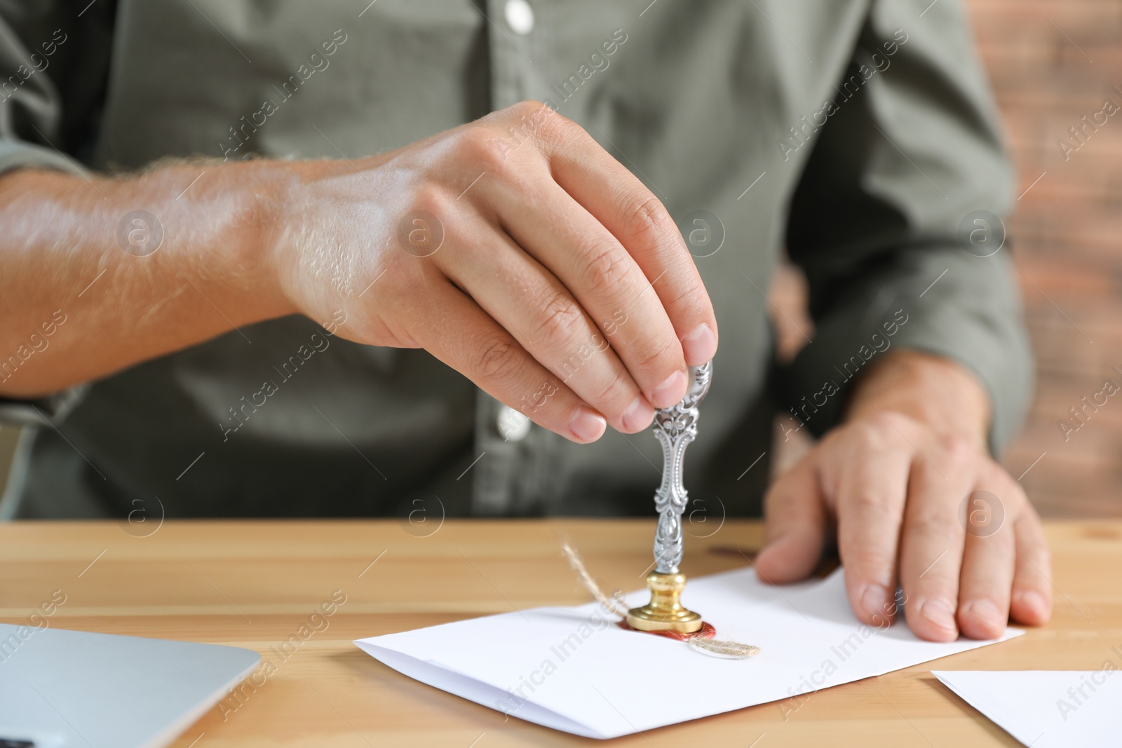 Photo of Male notary stamping document at table, closeup