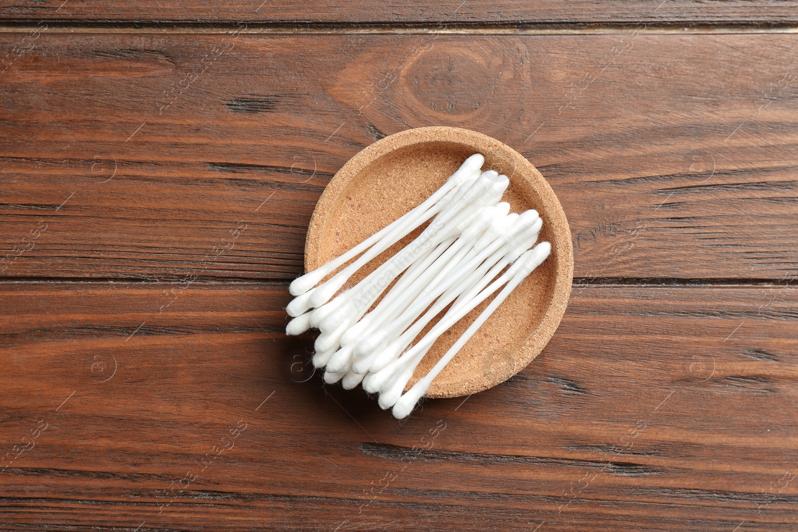 Photo of Plate with cotton swabs on wooden background, top view