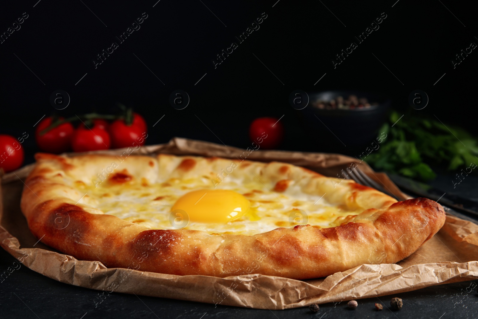 Photo of Fresh delicious Adjarian khachapuri served on black table