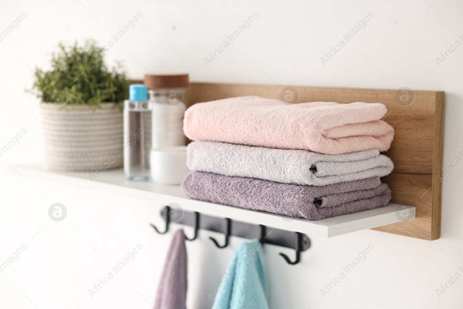 Photo of Clean towels, houseplant and toiletries on shelf indoors