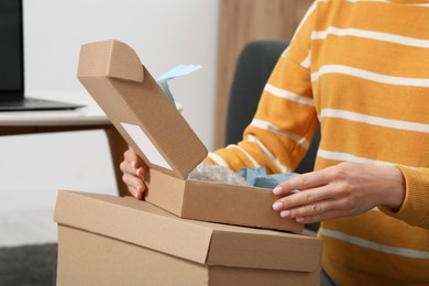 Photo of Woman unpacking parcel at home, closeup. Online store