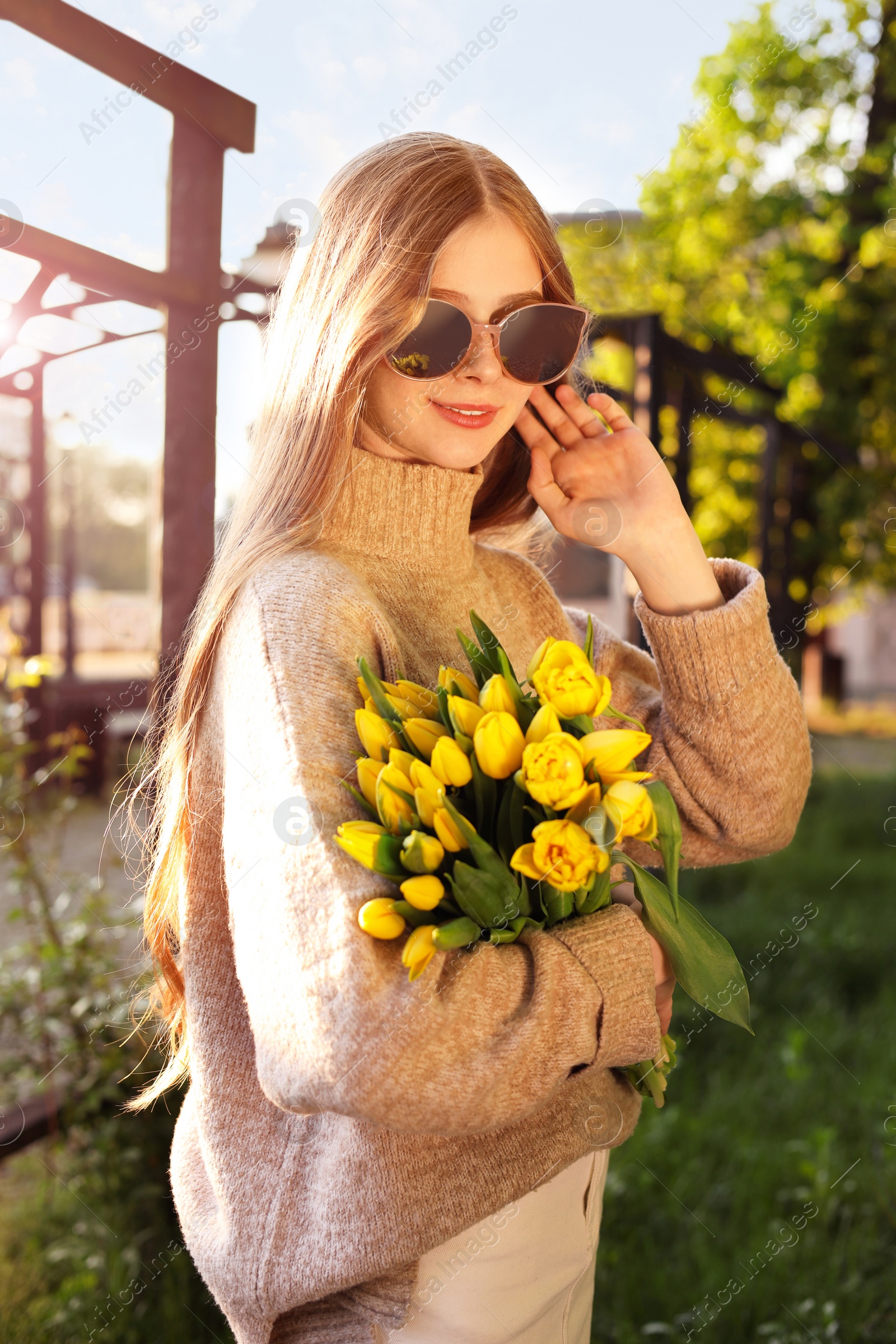 Photo of Beautiful teenage girl with bouquet of yellow tulips in park on sunny day