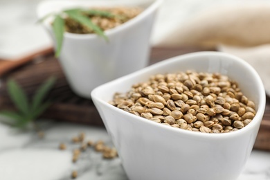 Photo of Organic hemp seeds in bowl on table, closeup