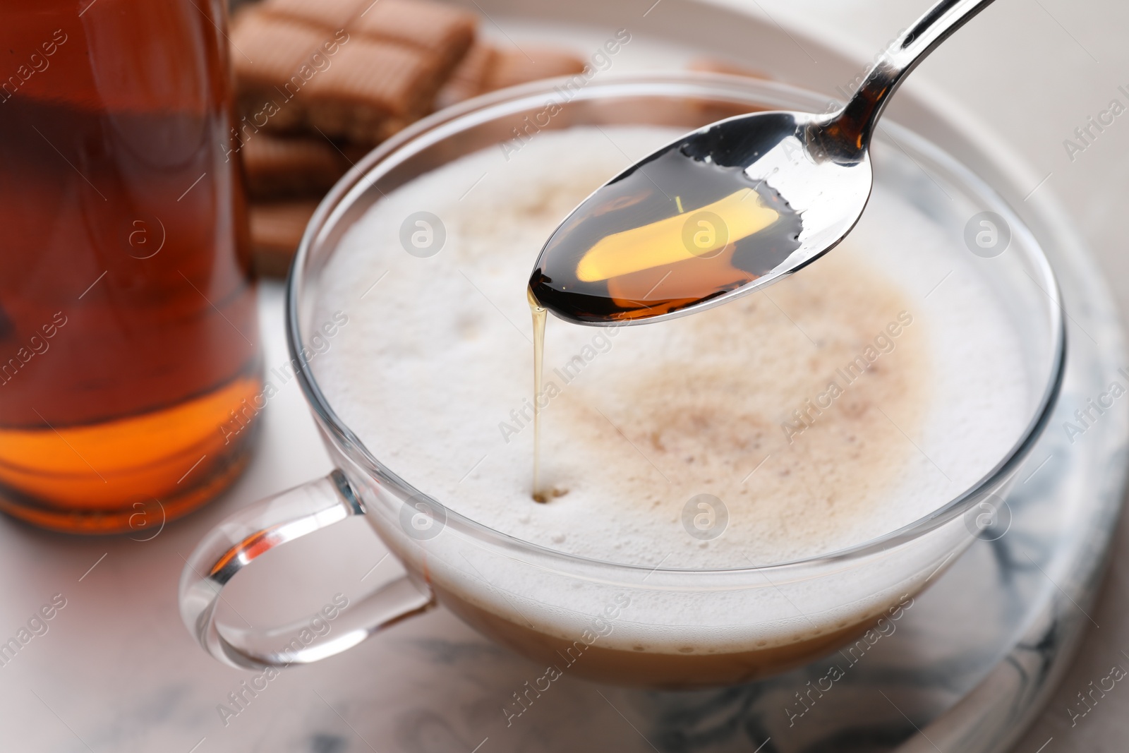 Photo of Pouring syrup into glass of tasty coffee, closeup