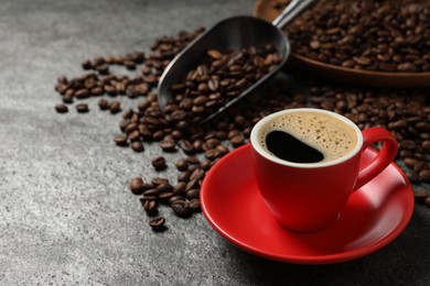 Cup of aromatic coffee and beans on grey table. Space for text