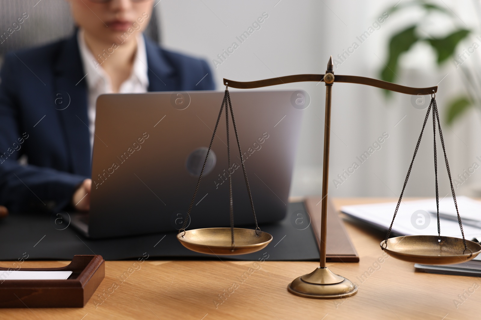 Photo of Notary working with laptop at table in office, focus on scales