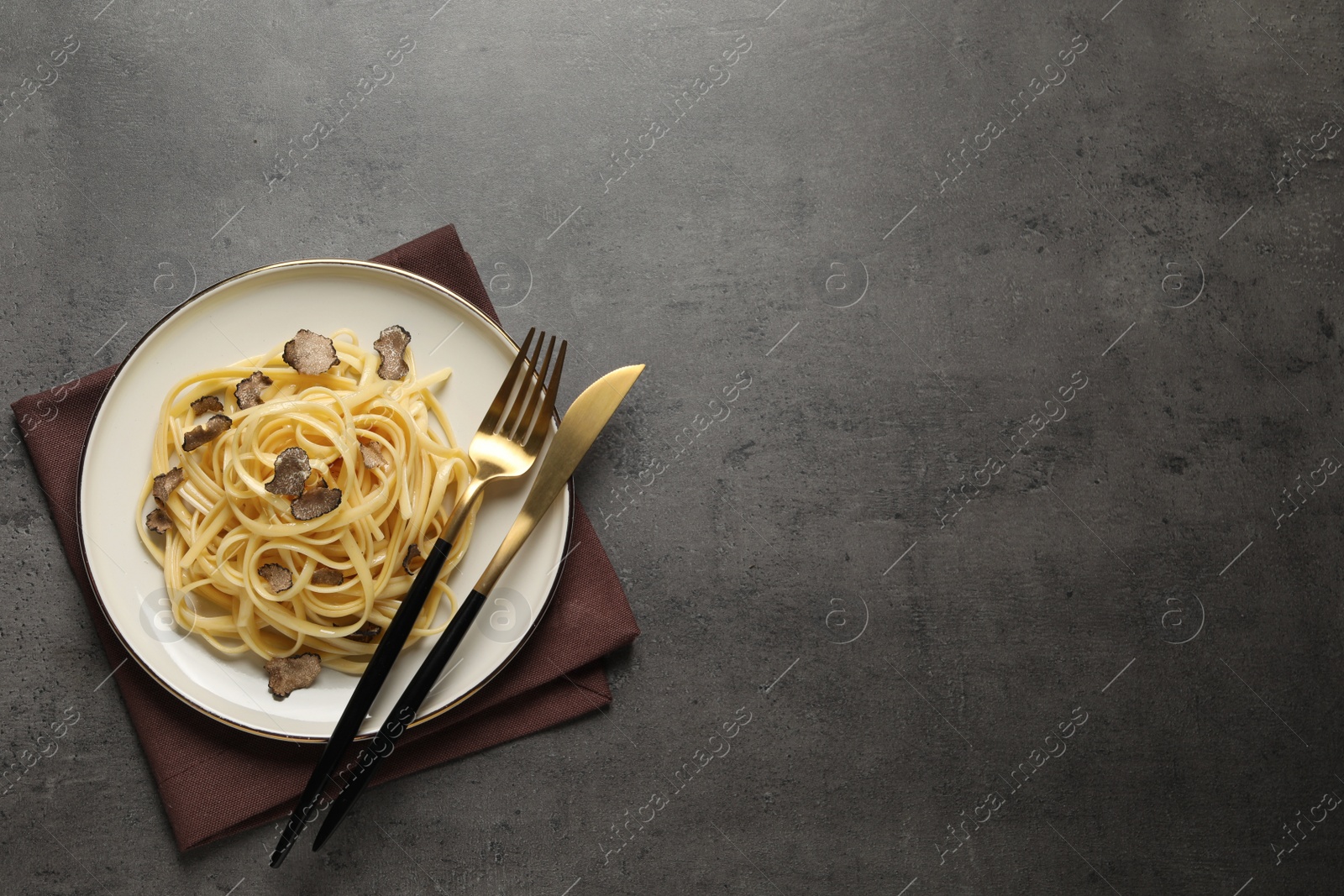 Photo of Tasty fettuccine with truffle on grey table, top view. Space for text