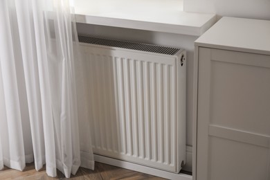 Photo of Modern radiator on white wall near window indoors