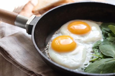 Delicious fried egg with spinach served on wooden table, closeup