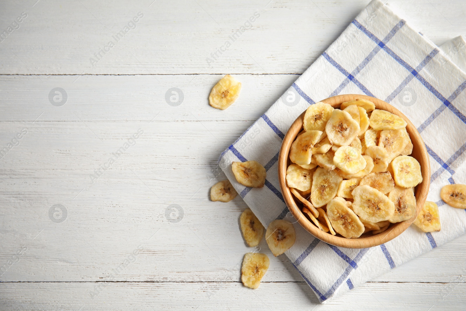 Photo of Wooden bowl with sweet banana slices on table, top view with space for text. Dried fruit as healthy snack