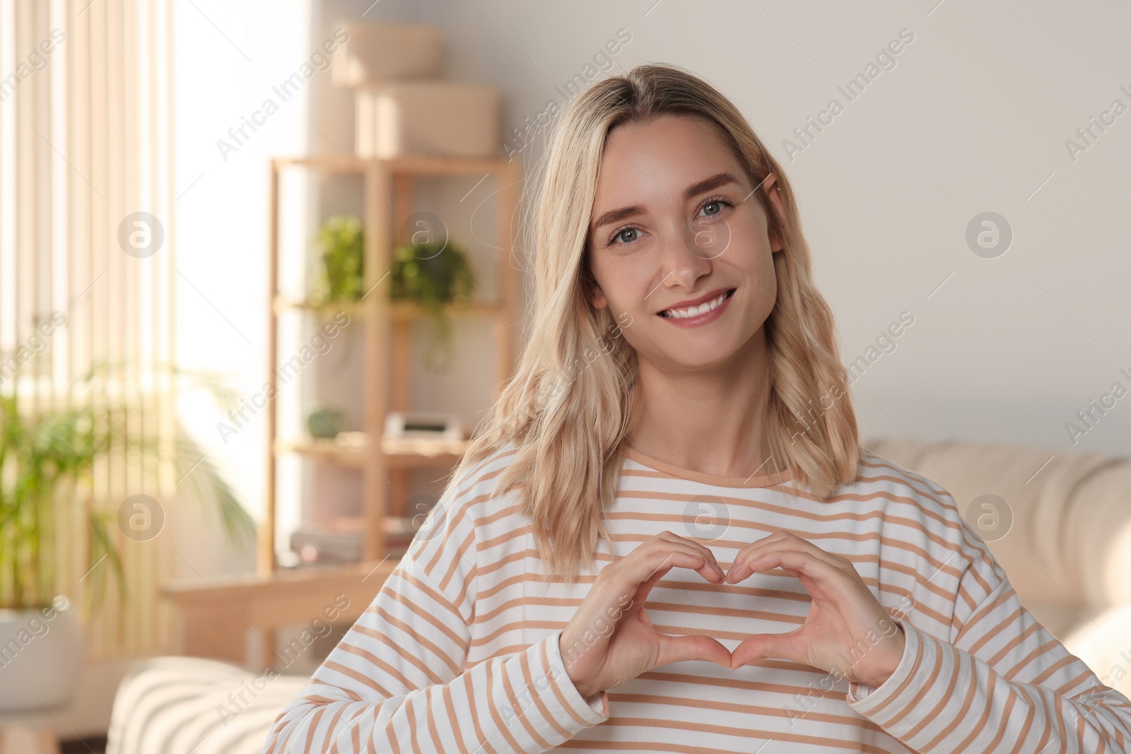 Photo of Happy volunteer making heart with her hands in room