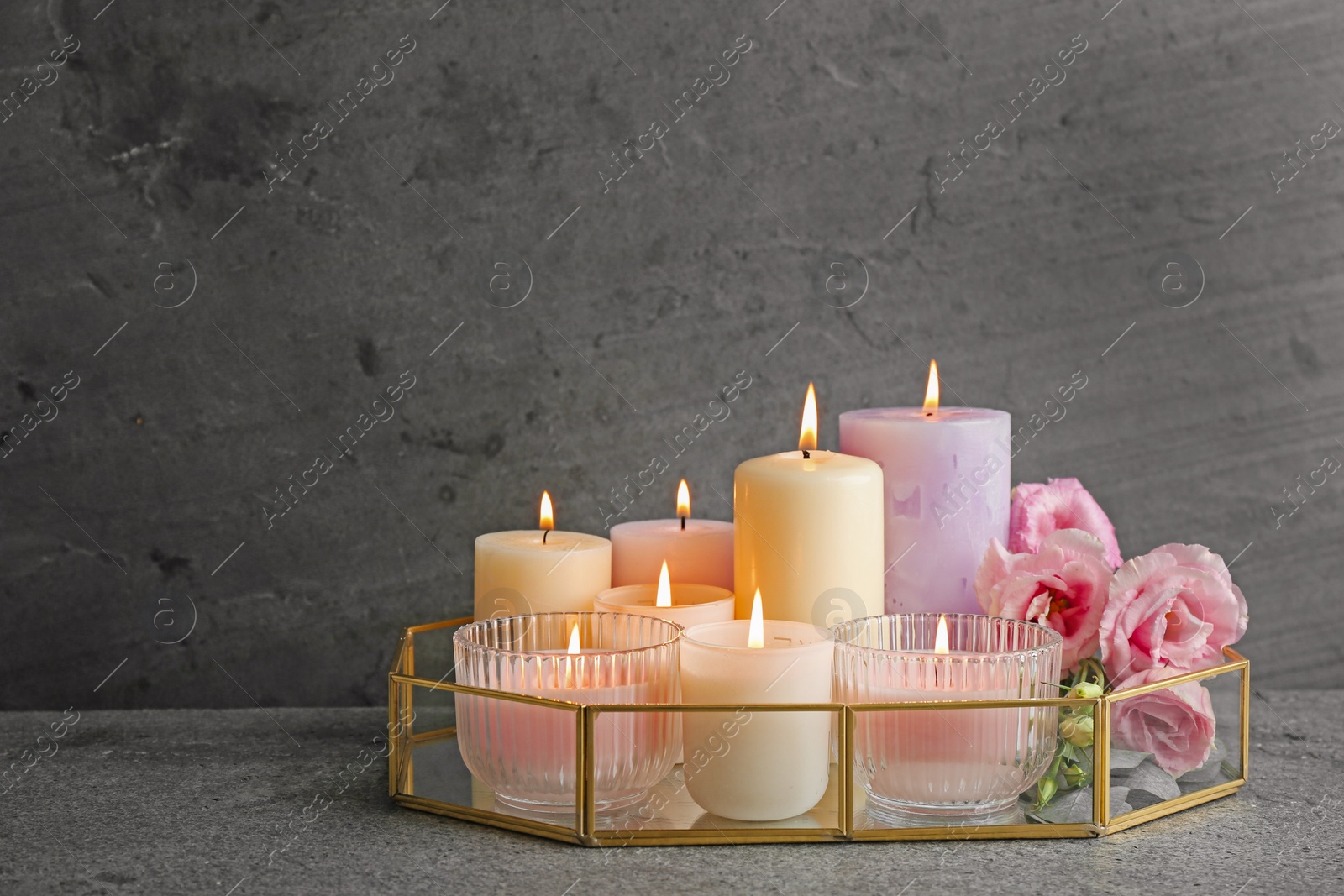 Photo of Composition with burning candles on table against grey background