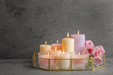 Composition with burning candles on table against grey background