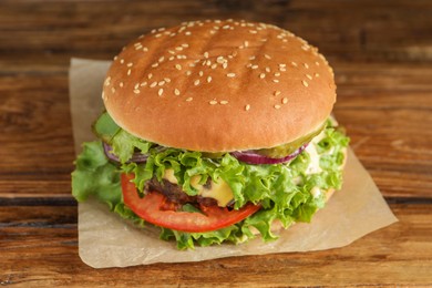 Photo of Delicious burger with beef patty and lettuce on wooden table