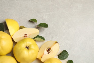 Fresh ripe organic quinces with leaves on grey table, flat lay. Space for text