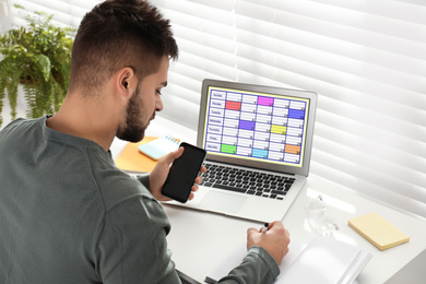 Photo of Young man planning his schedule with calendar app on laptop in office
