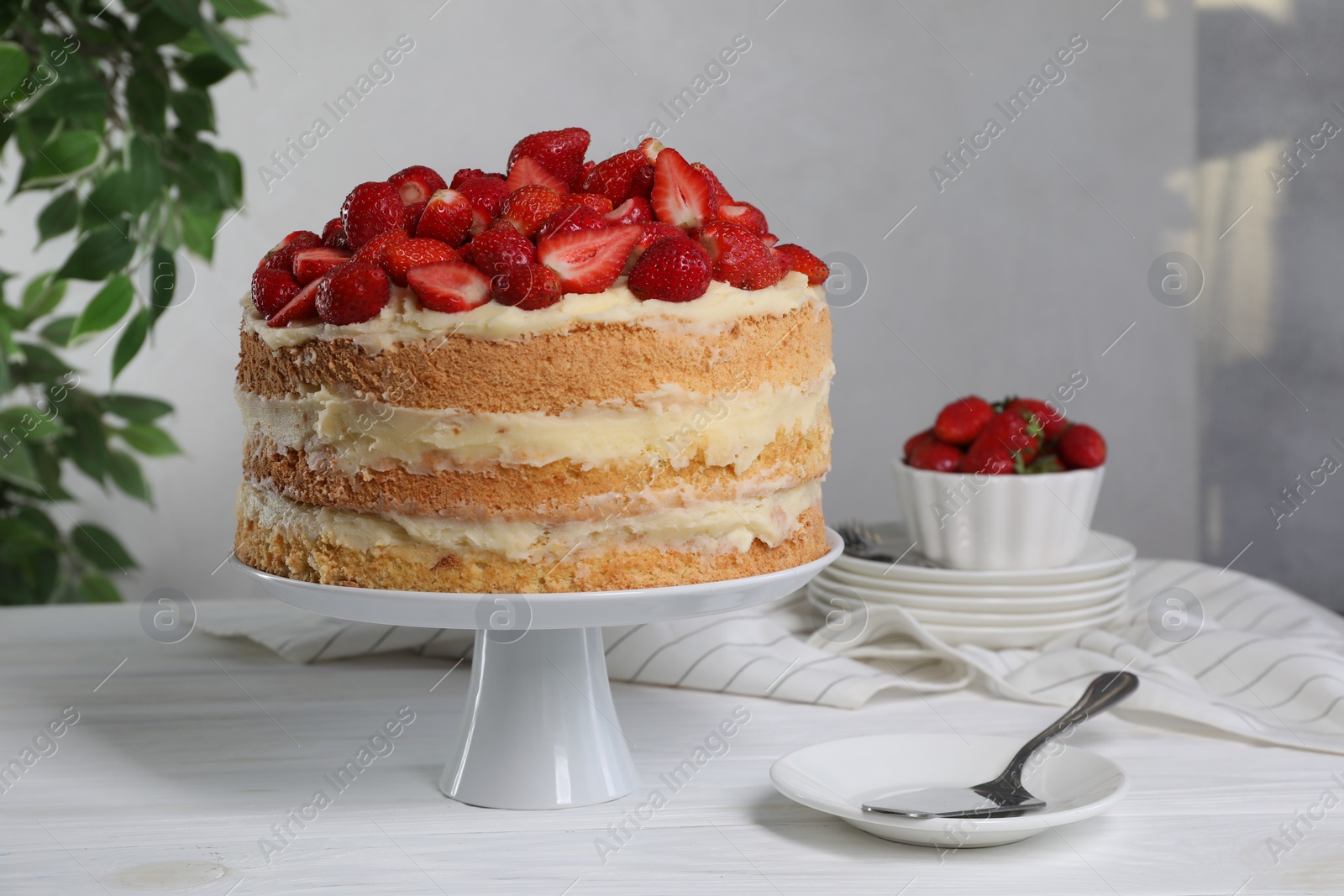 Photo of Tasty cake with fresh strawberries served on white wooden table