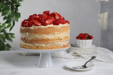 Tasty cake with fresh strawberries served on white wooden table