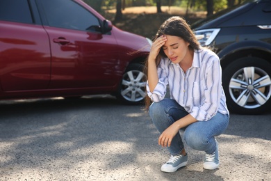 Photo of Stressed woman near cars after traffic accident outdoors