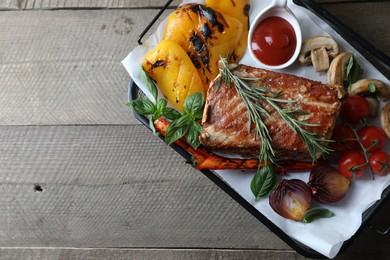 Delicious grilled meat and vegetables served with sauce on wooden table, top view. Space for text