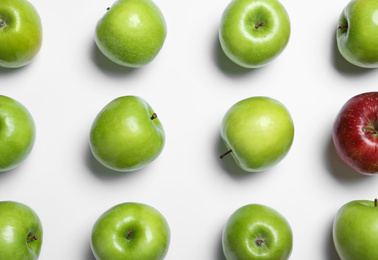 Photo of Red apple among green ones on white background, top view