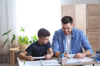 Dad helping his son with homework in room