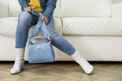 Photo of Woman in stylish leather shoes with bag on sofa indoors, closeup