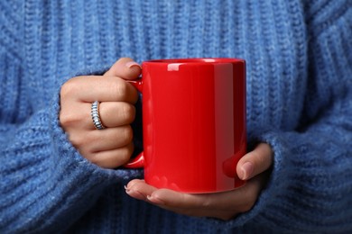 Woman holding red mug, closeup. Mockup for design