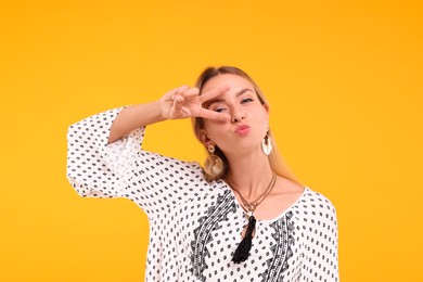 Photo of Portraithippie woman showing peace sign on yellow background