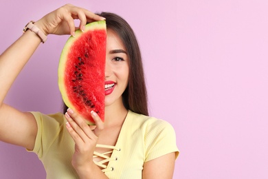 Beautiful young woman posing with watermelon on color background