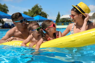 Photo of Happy family with inflatable mattress in swimming pool. Summer vacation