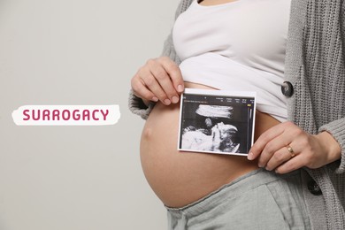 Surrogacy. Pregnant woman with ultrasound picture of baby on grey background, closeup