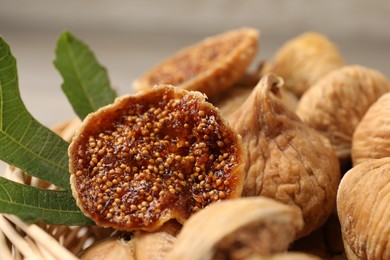 Photo of Tasty dried figs and green leaf in wicker basket, closeup