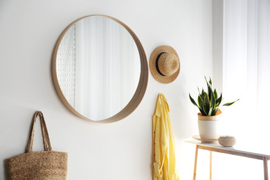 Round mirror with wooden frame on white wall in light room