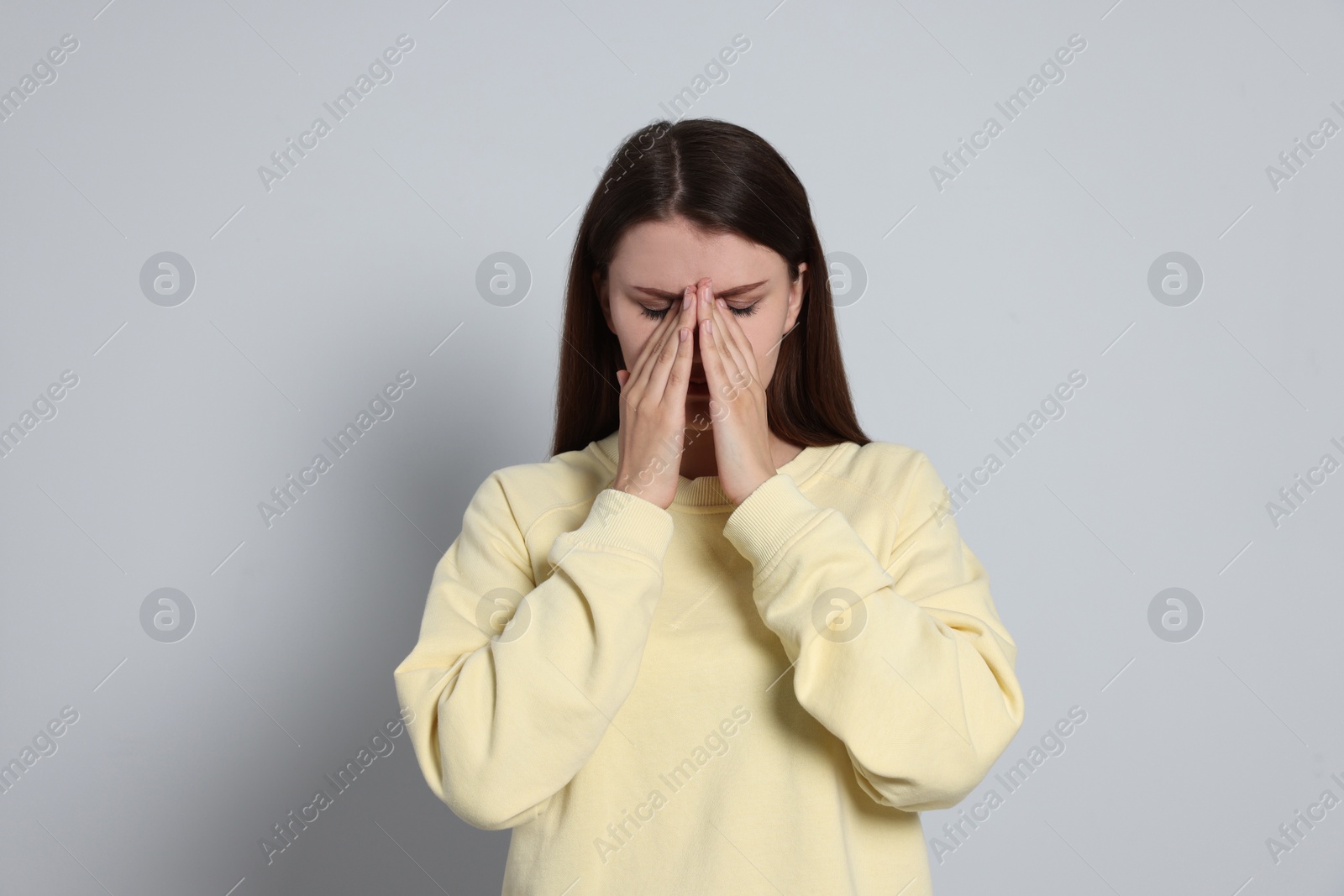 Photo of Young woman suffering from eyestrain on light background