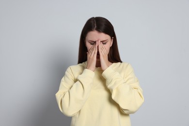 Young woman suffering from eyestrain on light background