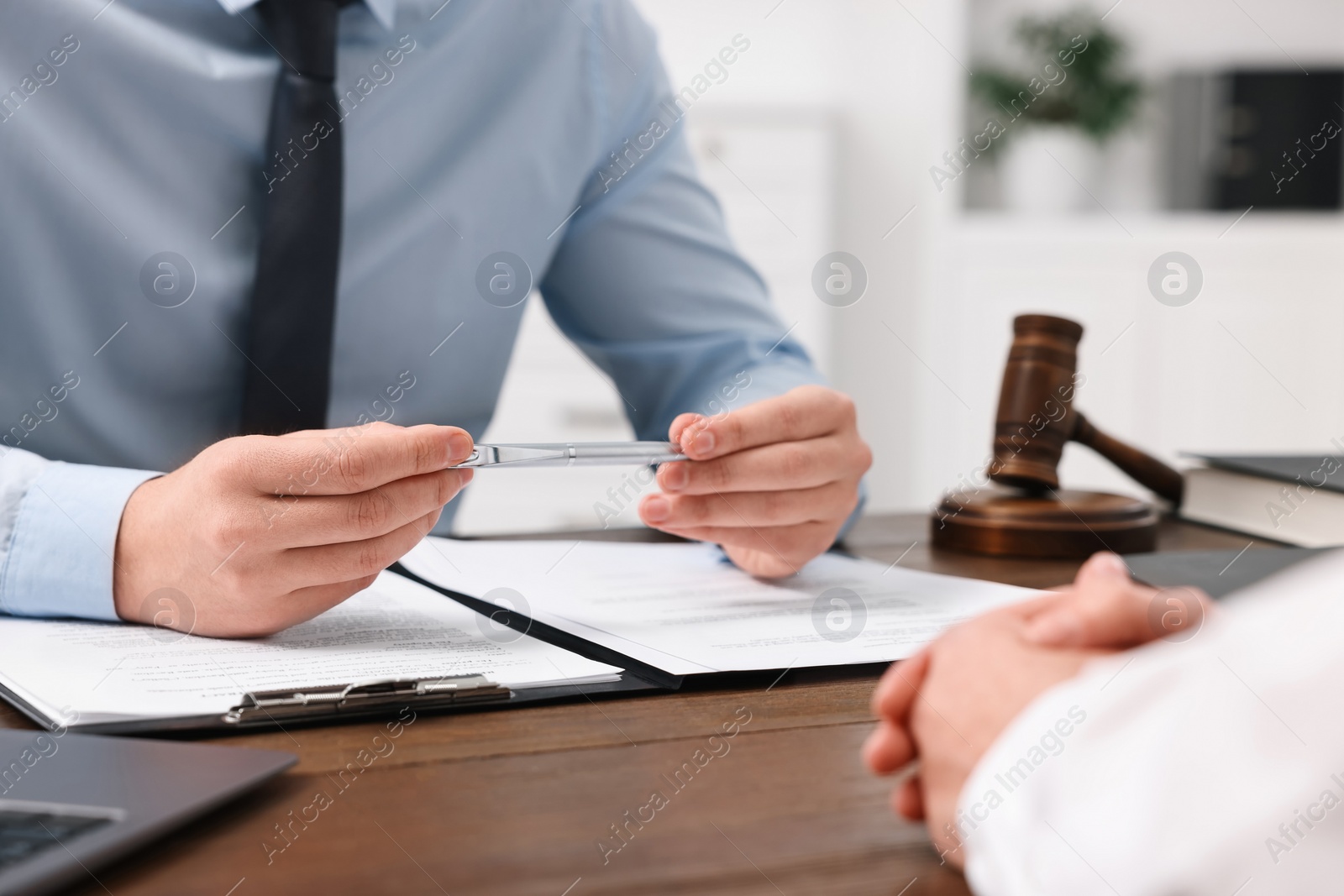 Photo of Lawyers working with documents at wooden table in office, closeup