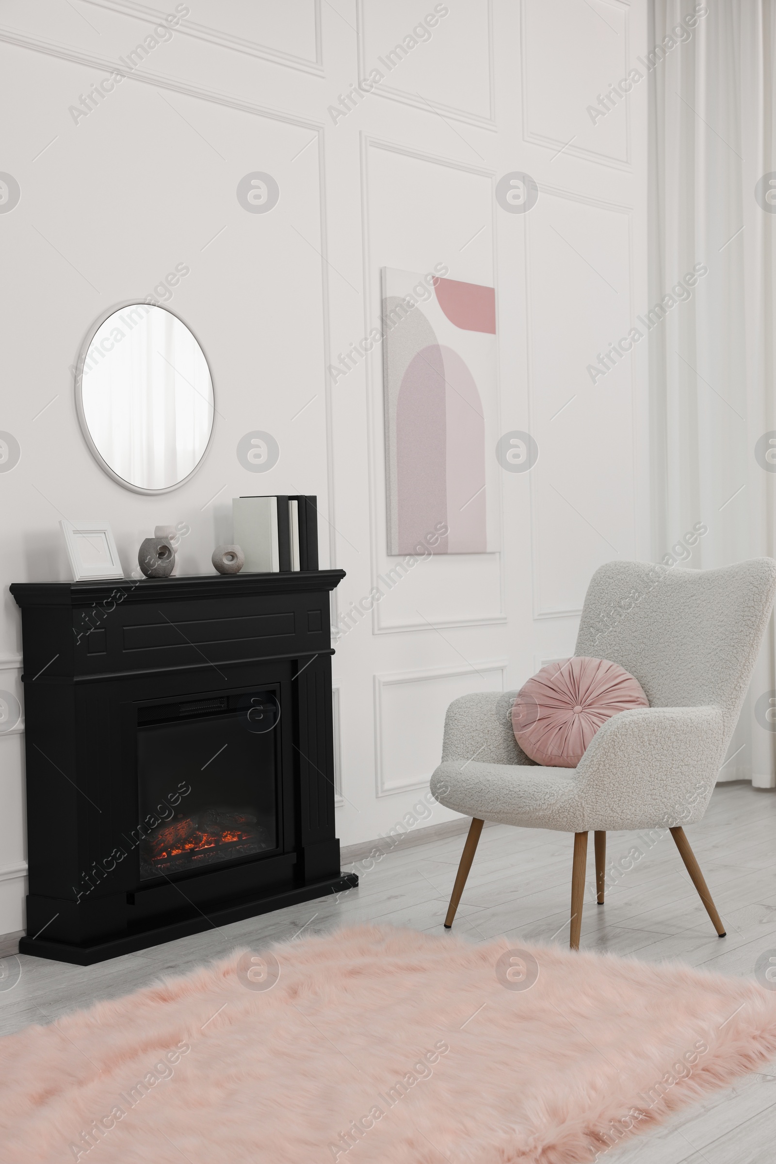 Photo of Black stylish fireplace near soft armchair in cosy living room