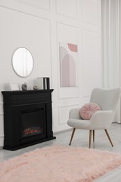 Photo of Black stylish fireplace near soft armchair in cosy living room