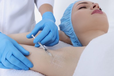 Photo of Cosmetologist injecting young woman's armpit, closeup. Treatment of hyperhidrosis