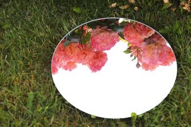 Photo of Round mirror on grass reflecting beautiful flowers and sky