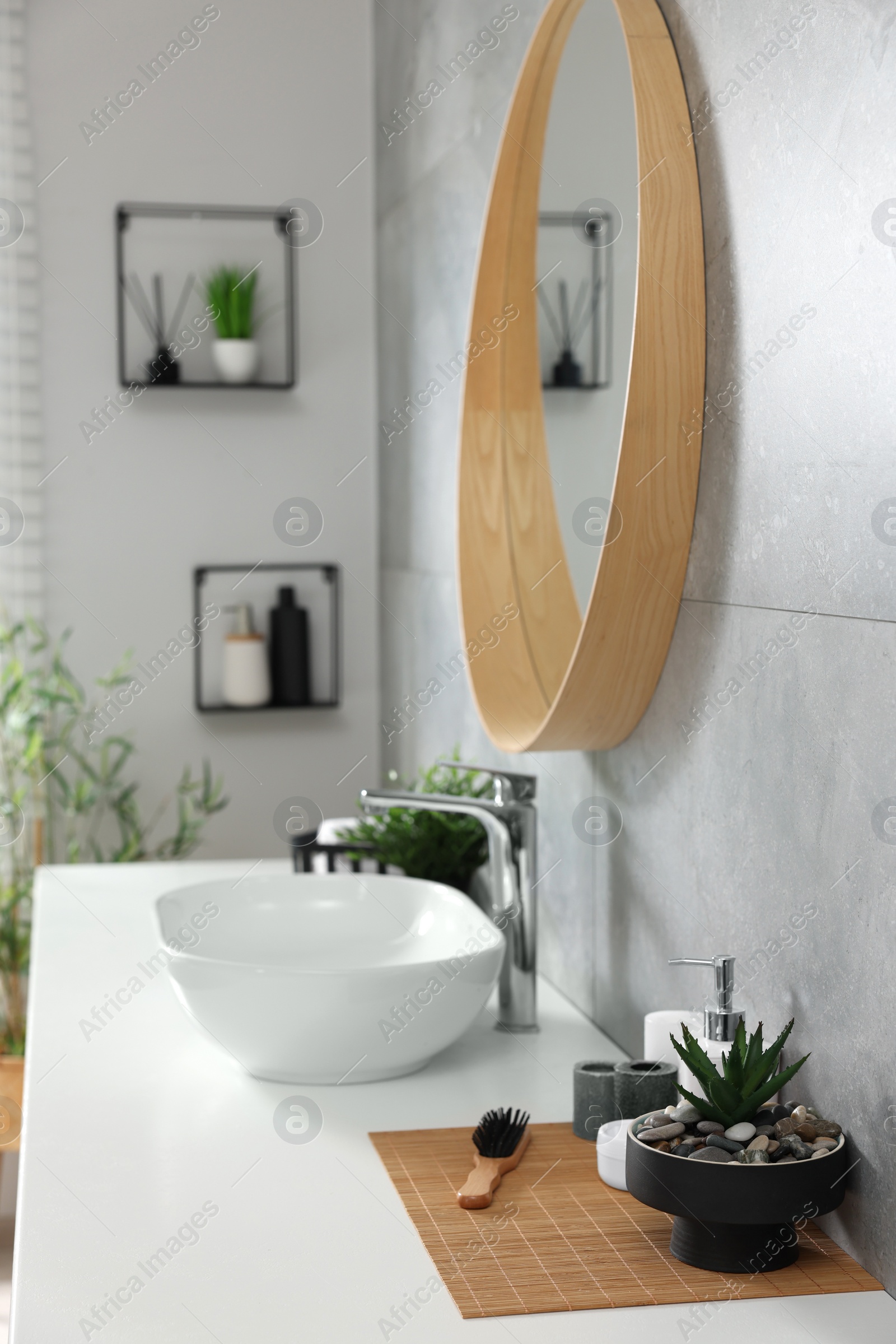 Photo of Potted artificial plants and toiletries near sink on bathroom vanity