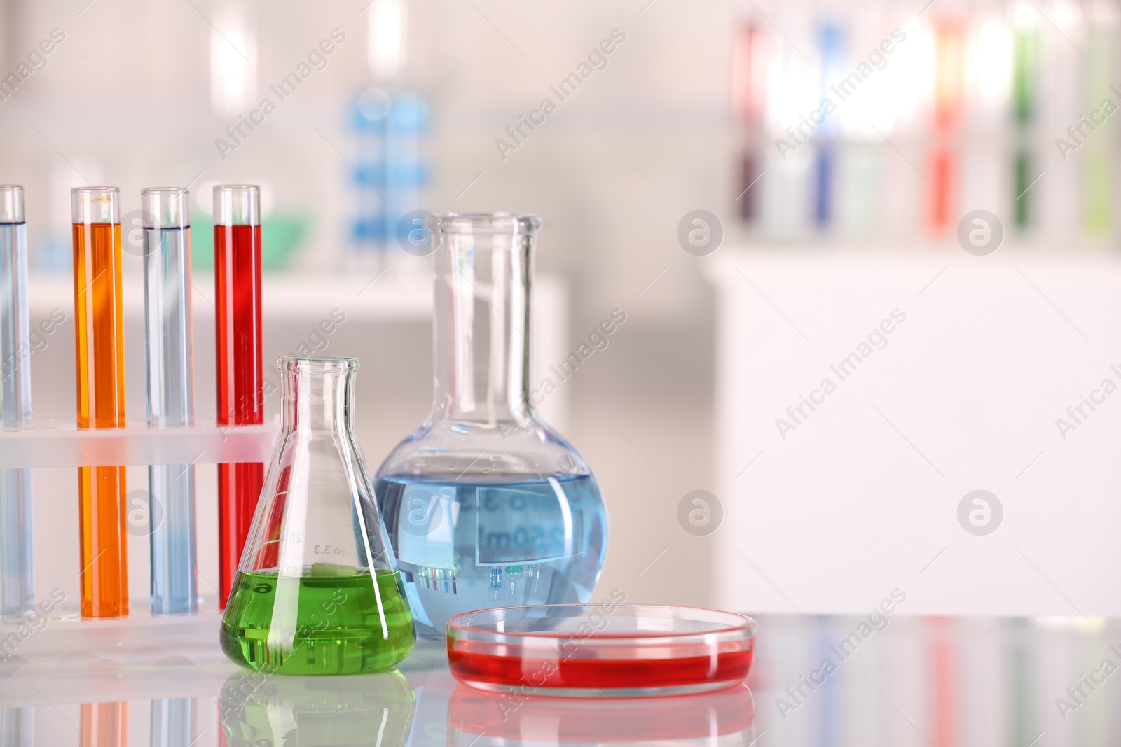 Photo of Laboratory analysis. Different glassware with liquids on white table against blurred background. Space for text