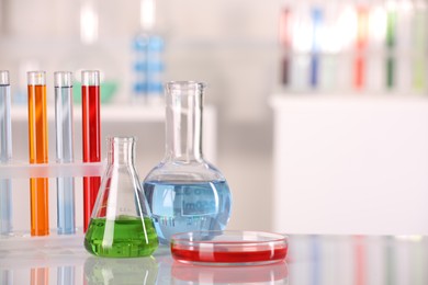 Laboratory analysis. Different glassware with liquids on white table against blurred background. Space for text