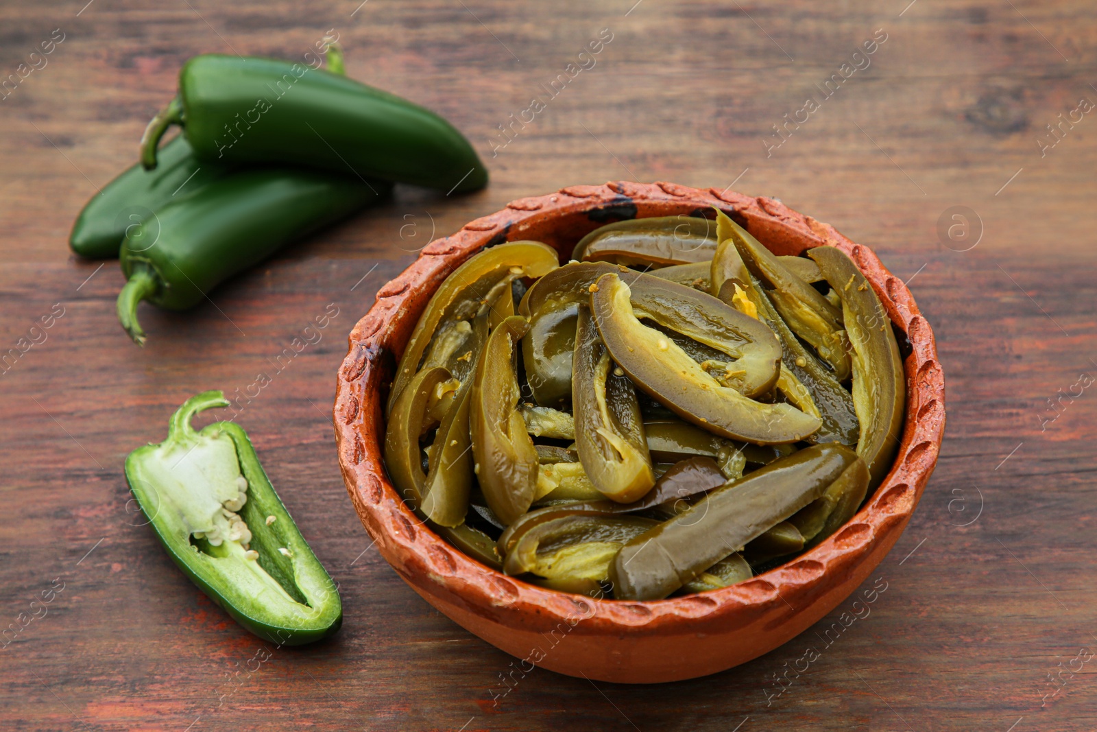 Photo of Fresh and pickled green jalapeno peppers on wooden table